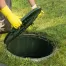 a homeowner opening the lid of septic tank to check for problems and maintain the system