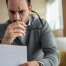 Man looking concerned as he's looking over insurance paperwork.